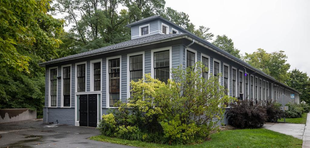 Long gray building surrounded by greenery.