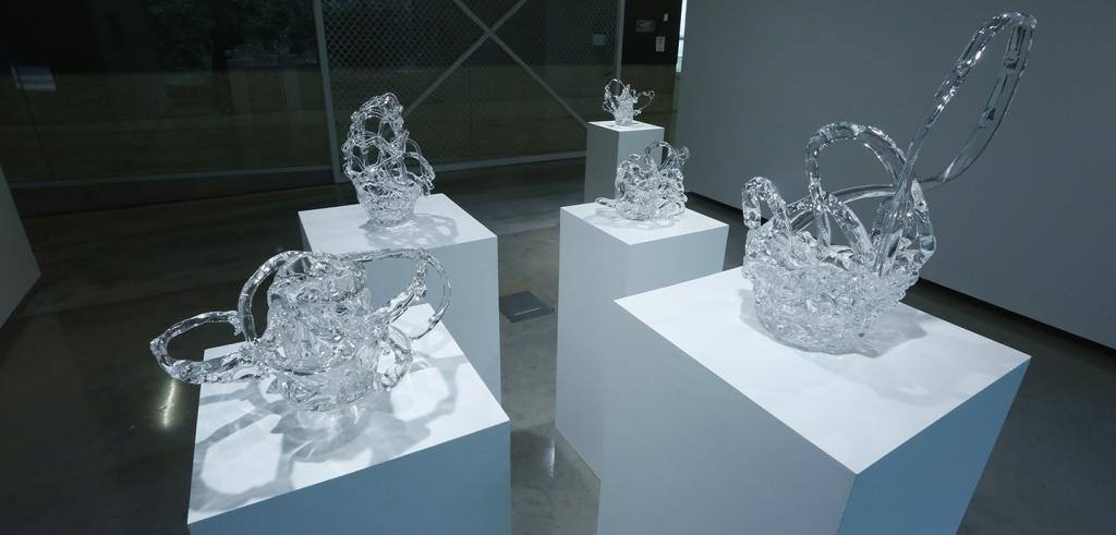 Glass sculptures on white pedestals.