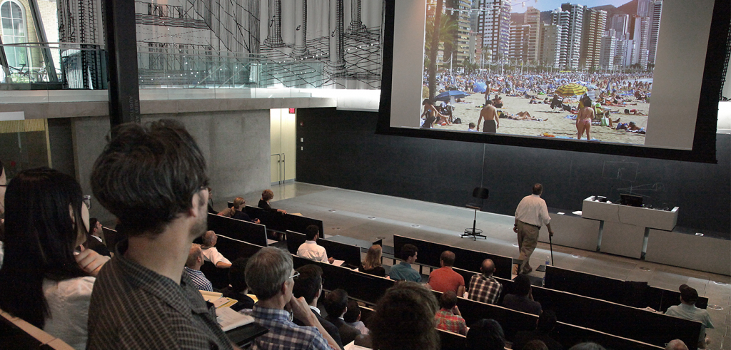photo of people in lecture hall with photo in giant projector