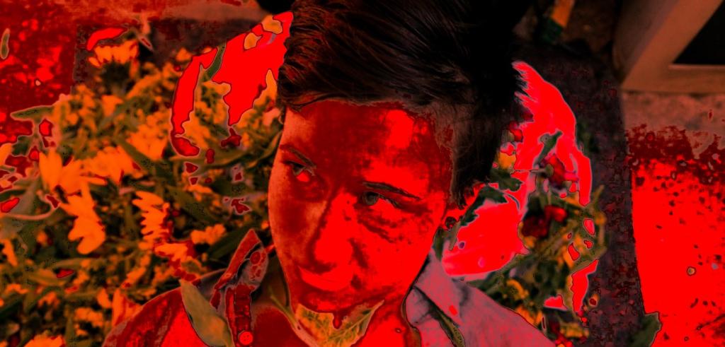 Photo of the artist with a red filter over it, looking to the side. 