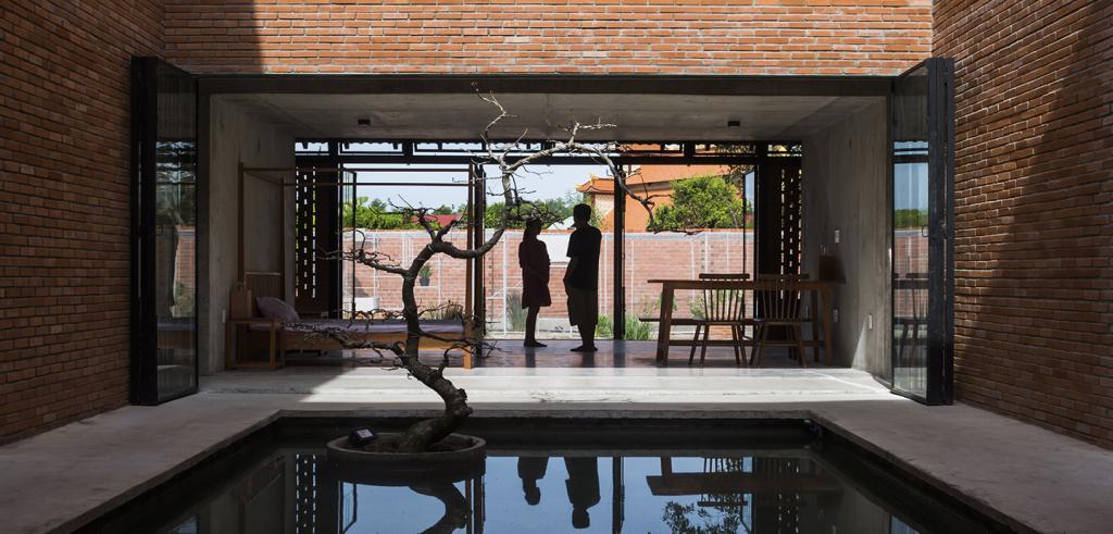 Brick building containing a concrete pool with water.