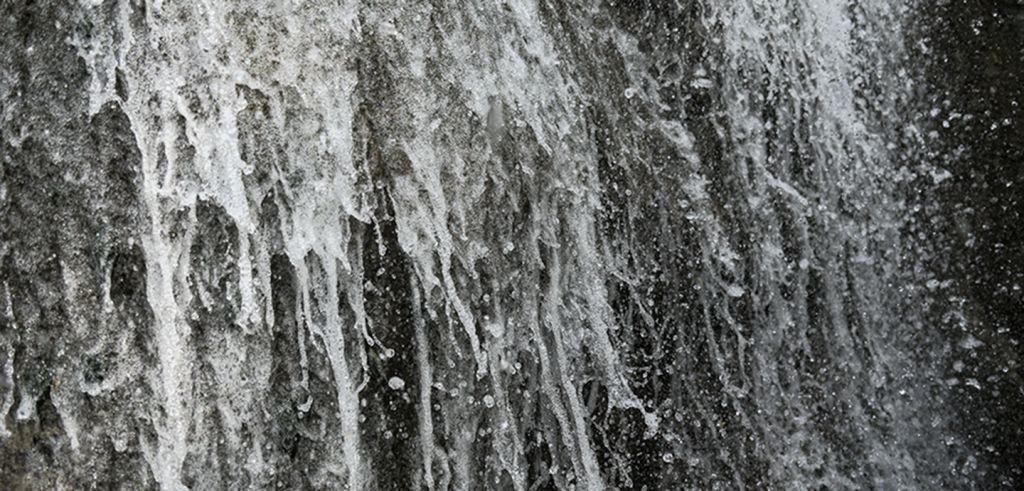 A black and white close-up photograph of a rushing waterfall.