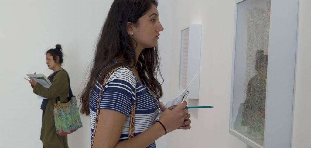 Two women taking notes in an art gallery.