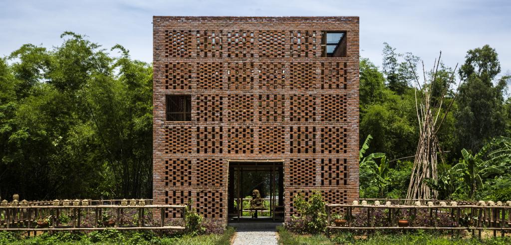 square building made of terra cotta with small decorative square sections surrounded by forest