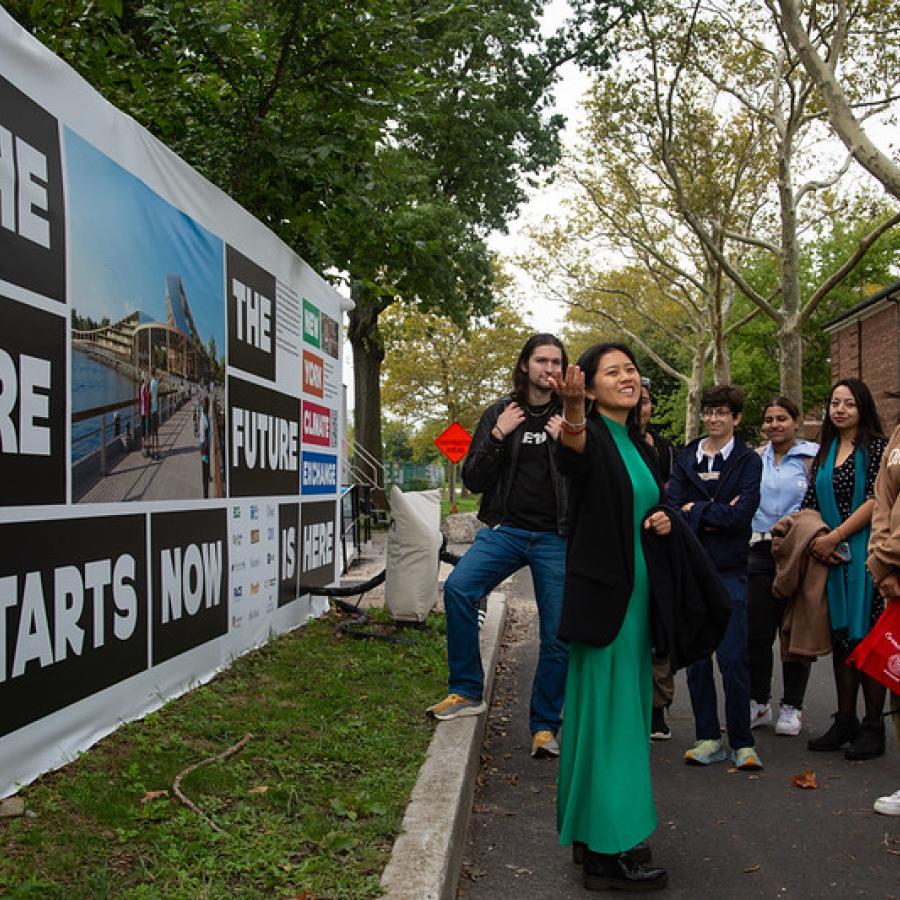 a group of people observing a person speaking and showcasing a mural behind them