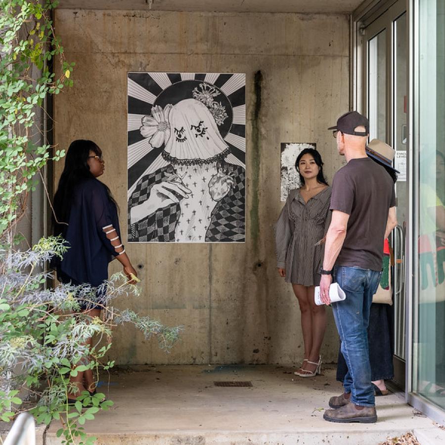 a group of people standing together observing an artwork hung on the wall