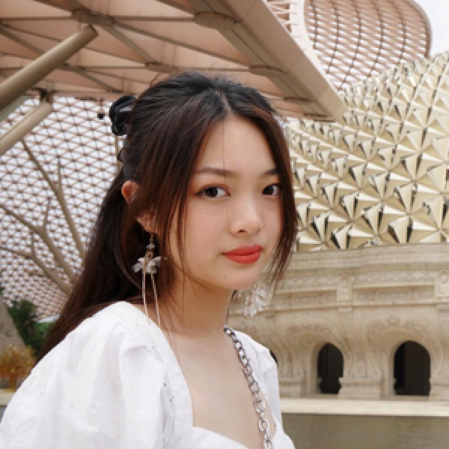 student with long dark hair white outfit outside among architecture