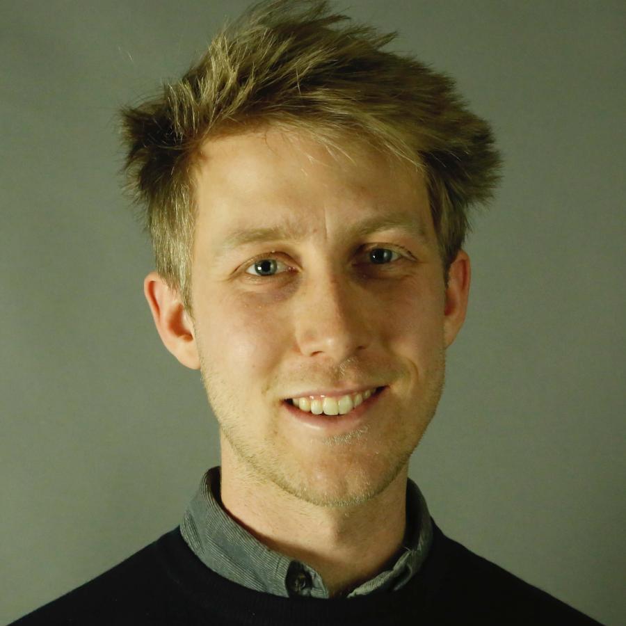 A person wearing a dark black shirt and a grey collared shirt.