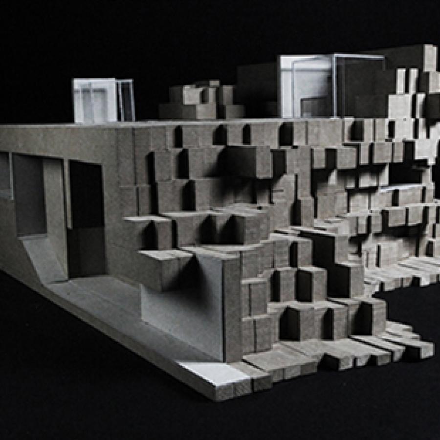 Photograph of model made from paper, basswood, and chipboard layered together into vertical sections of chipboard assembled into a topological mass.
