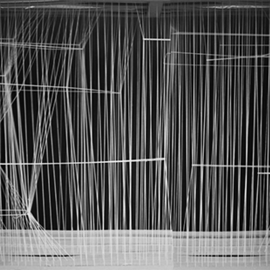 Photograph on black background of model made of thin white strings held in tension to create varying densities, translucency, and shapes.
