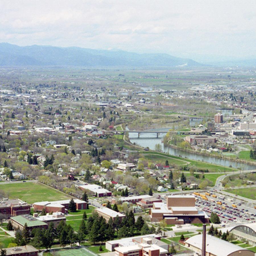 city with a river running through it and mountains in the background