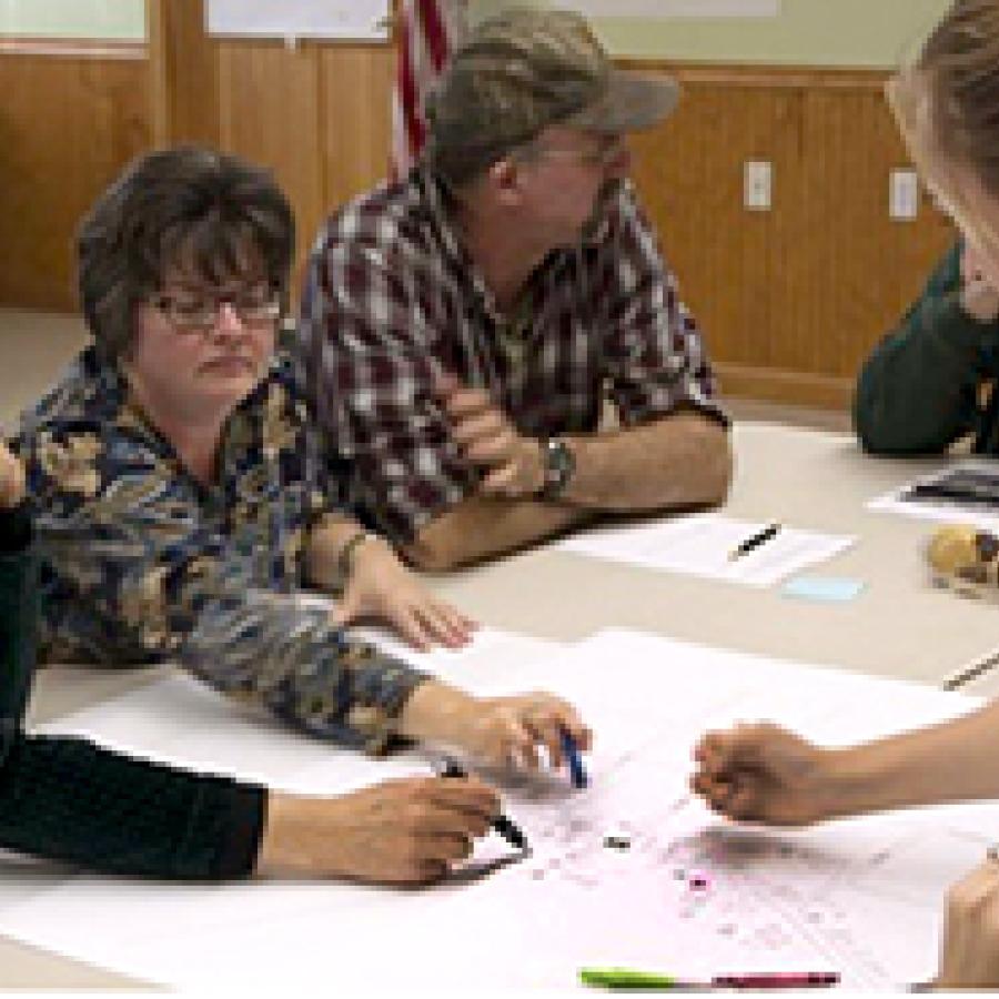 people gathered around a desk working on a project involving paper and markers