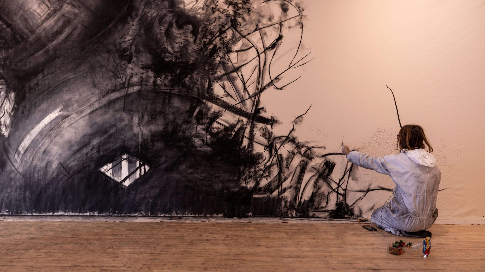 A person kneeling down and painting on a wall.
