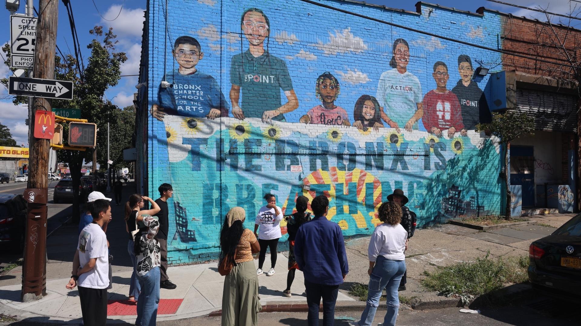 A group of students gather around a mural in the South Bronx