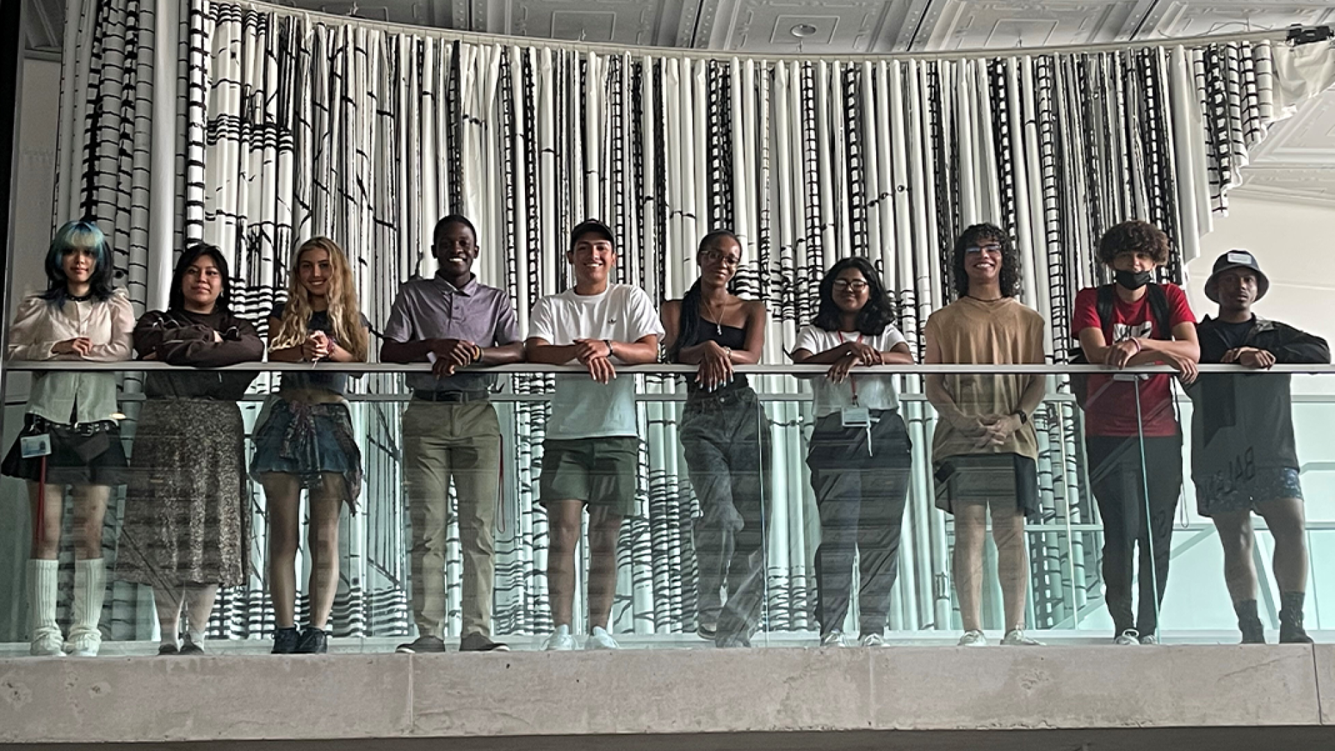 People standing at the edge of a glass staircase railing.