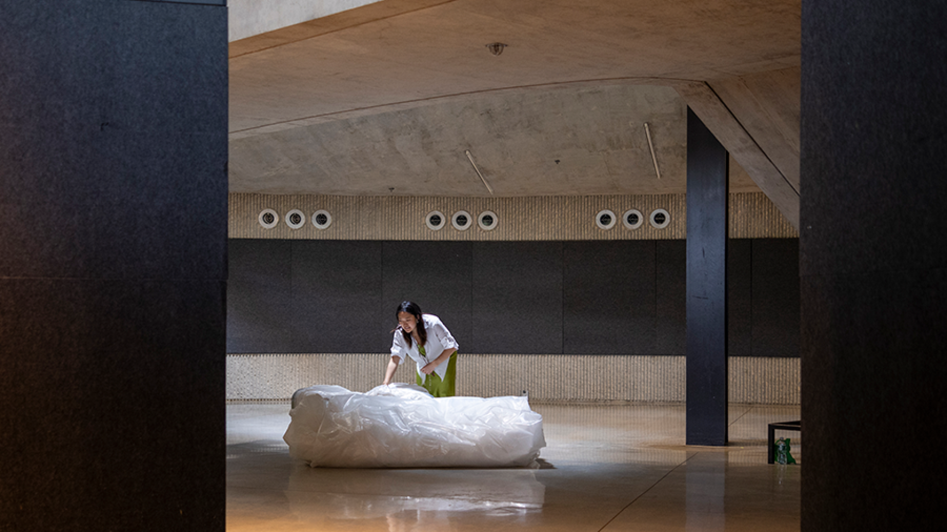 a person bending over observing a large white object in the middle of the floor