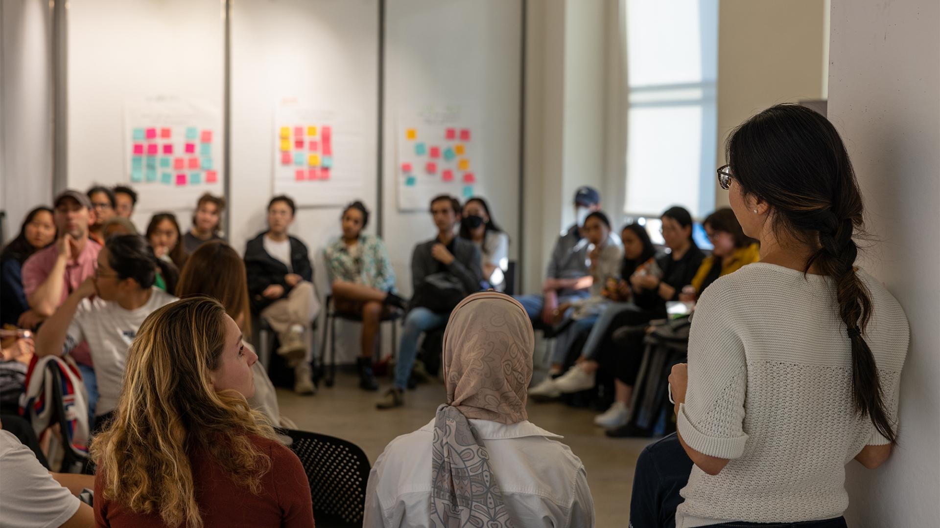 A group of students inside a room with sticky notes on the walls.