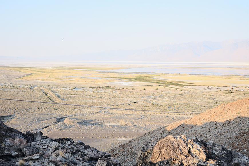 A large barren landscape with a lake in the background with the sky and water blending together in light colors.