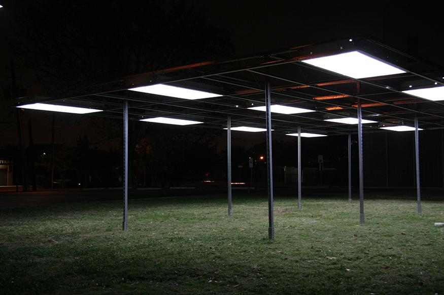 An outdoor installation in the form of a pavilion whose roof consists of a series of rectangular office lights