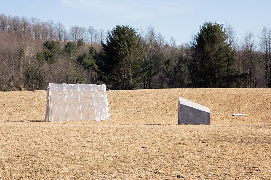 A clear tent situated in a valley of dry grass. 