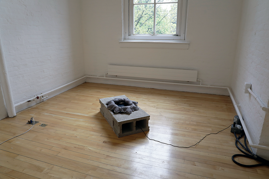 A concrete block on a light wooden floor, with a circular sculpture on top of it.