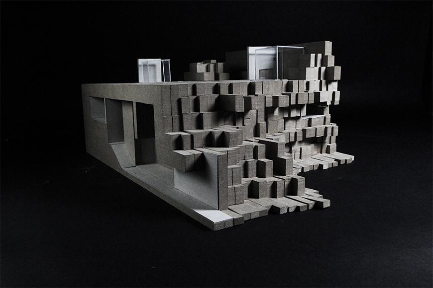 Photograph of model made from paper, basswood, and chipboard layered together into vertical sections of chipboard assembled into a topological mass.