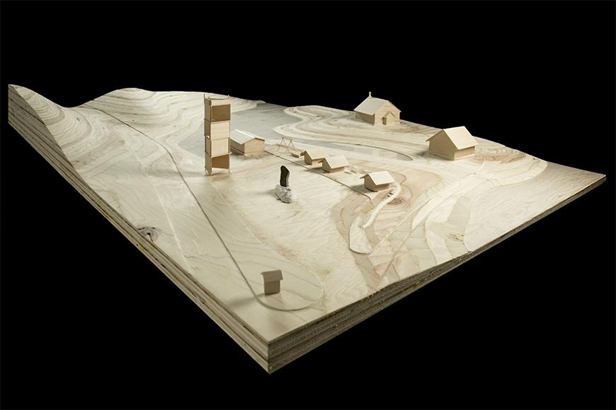 Photograph of site model made of milled wood topology with basswood buildings.