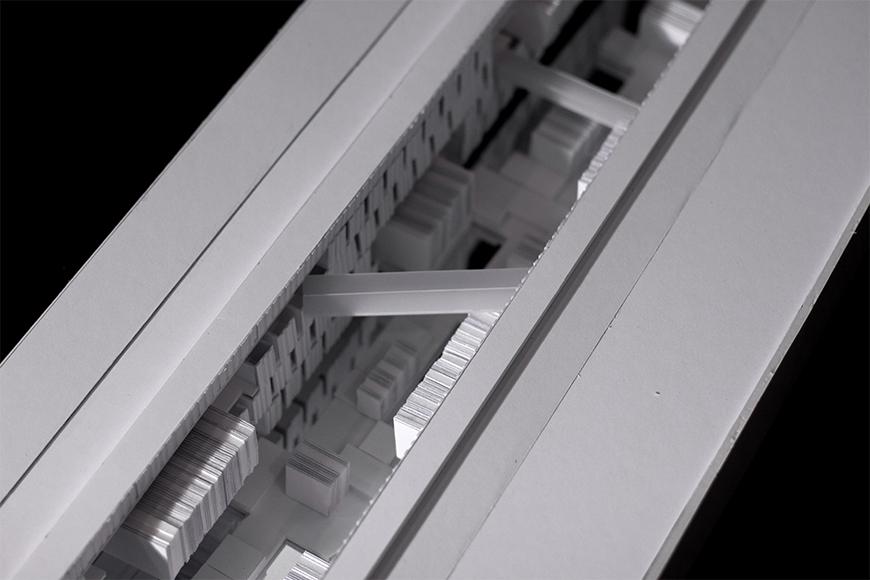 Black and white photograph of close-up of white model made of paper and paper products, showing sunken highly textured space.