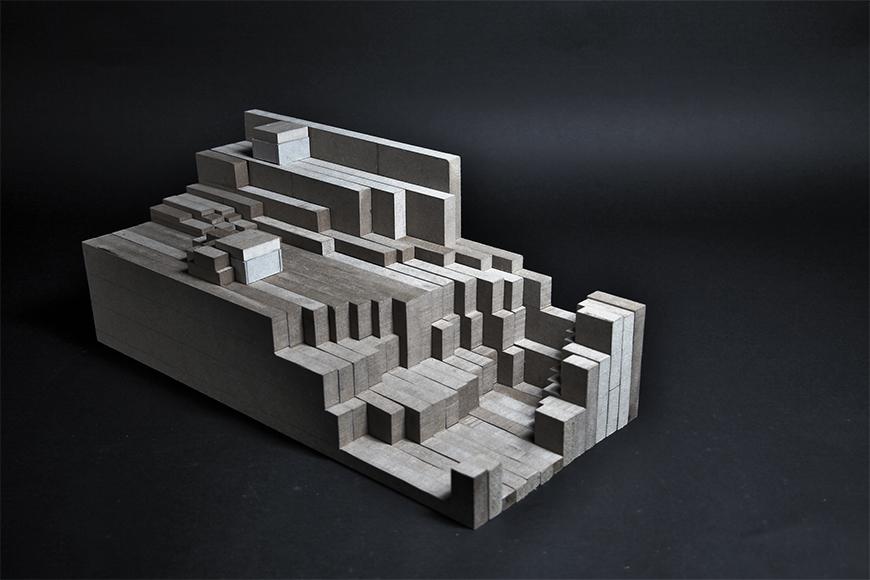 Photograph of model made from frosted plexiglass and vertical sections of composite wood boards assembled together to form a topological mass.