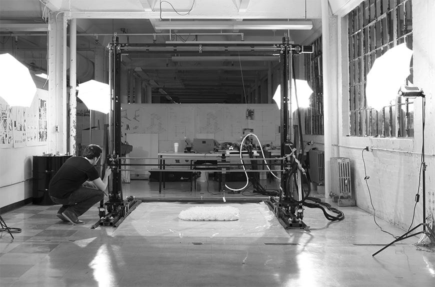 Black and white photograph of Chris Battaglia assembling 3D printer.