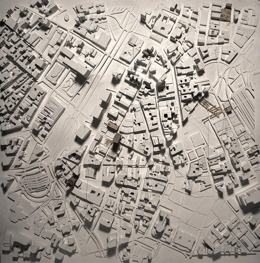 Photograph of white site model with places of intervation modeled in brown chipboard.