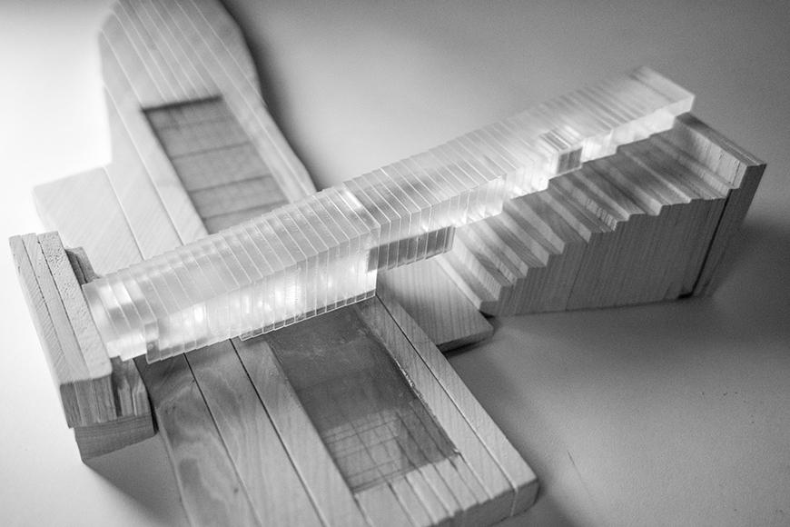 Black and white photograph of model made of wood for the site and a mass composed of vertical plexiglass layers glued together with opaque masses embedded within.