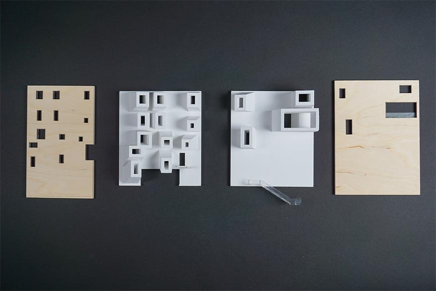 Photograph of wall components for project model showing wooden boards for the exterirors and a matte white material for the interior walls.