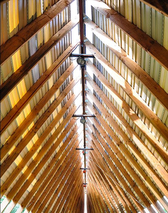 steeply pitched roof with approximately 40 wooden rafters seen from inside