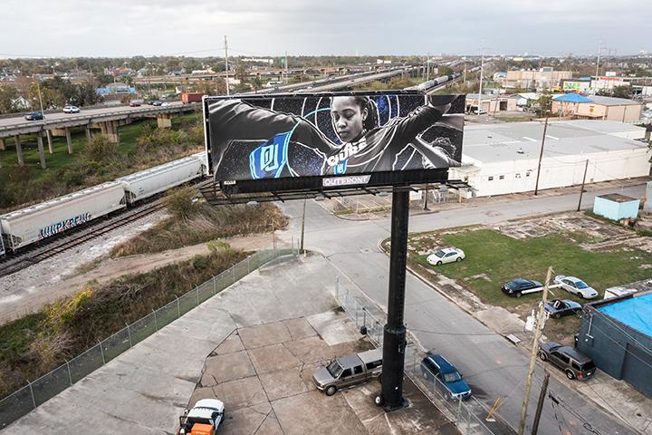 Aerial view of a billboard with a woman holding her arms out surrounded by a highway and parking lots