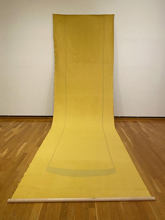 Long piece of yellow paper partly hanging on a wall and draped to the floor.