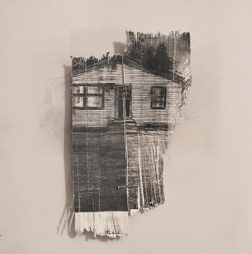 Black print of a small house on a piece of scrap paper.