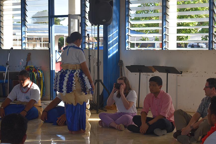 People sitting on the floor, being served something to drink from a bowl