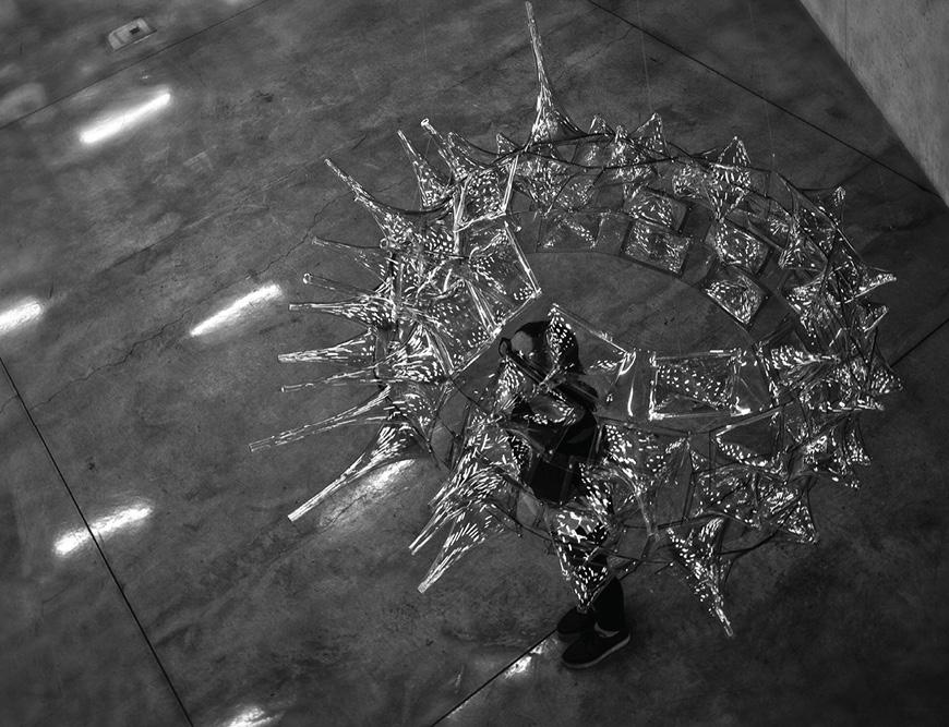 Person standing under spiky spherical model hanging from ceiling. 