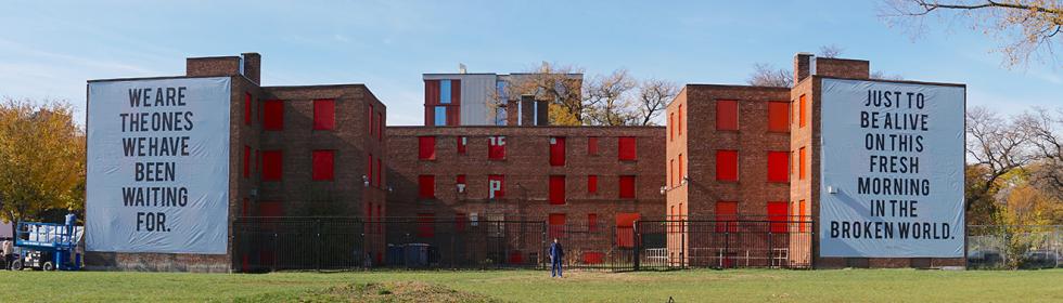 Building with red covered windows and two black and white signs hanging on both ends.