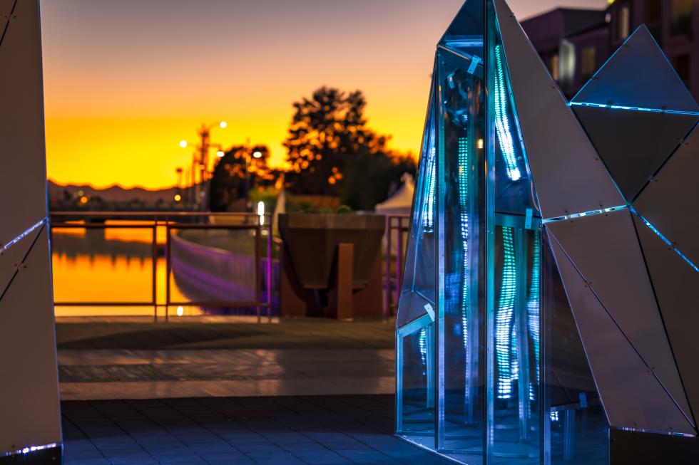 A photo of an LED lit art object overlooking a water scene.