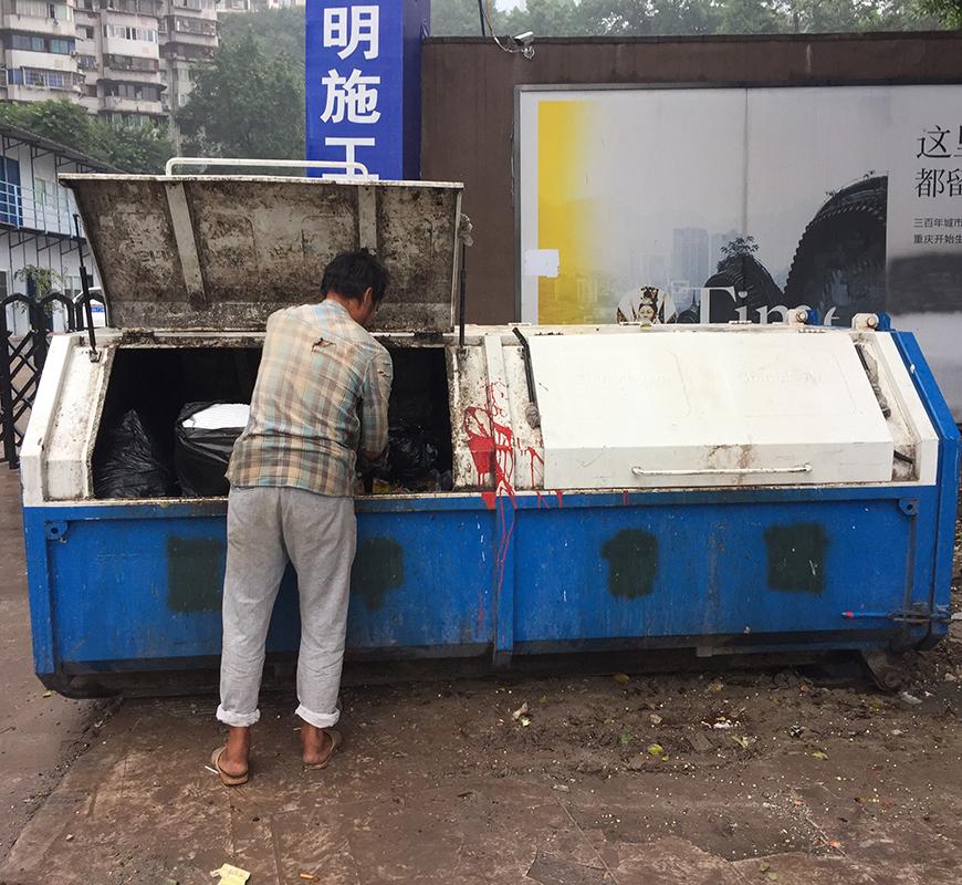 person sifting through contents of a dumpster