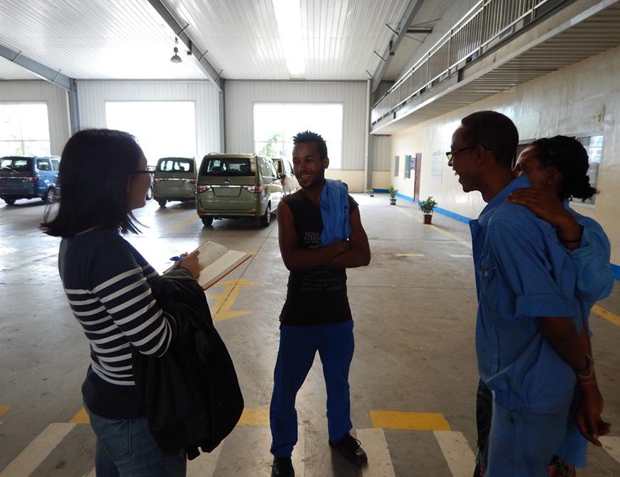 4 individuals in a parking garage in conversation. Ding in the striped sweater is taking notes.