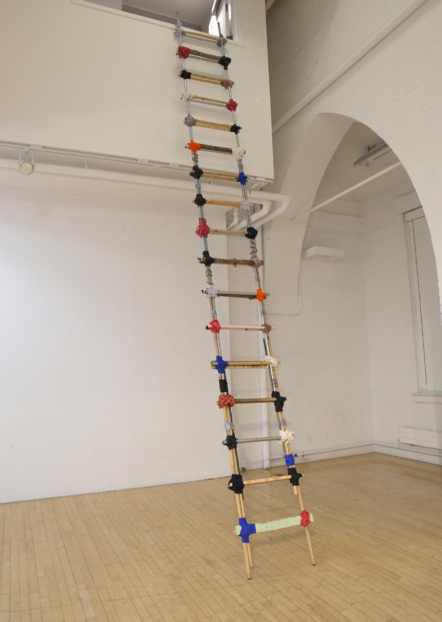 Multi-colored ladder made from various materials propped up against a wall.