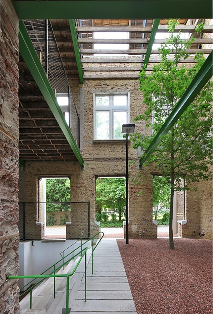 Inside a building whose interior has been removed, and opened to the outdoors. 