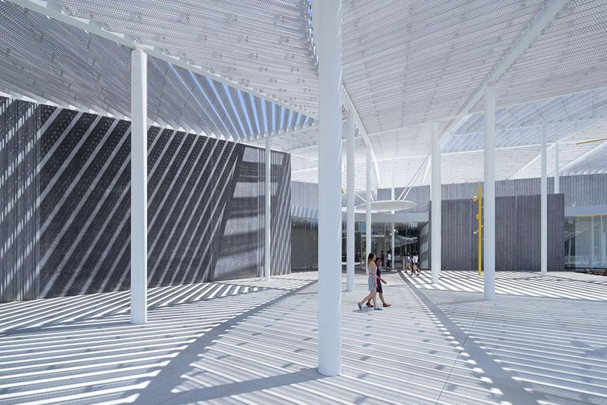 A white courtyard awning structure casting shadows on the ground.