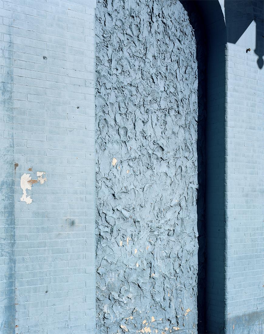 Vertical color photo of blue-grey bricks and textured concrete.