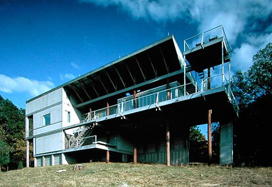 modern three-story home with extensive balconies supported by four pilings 