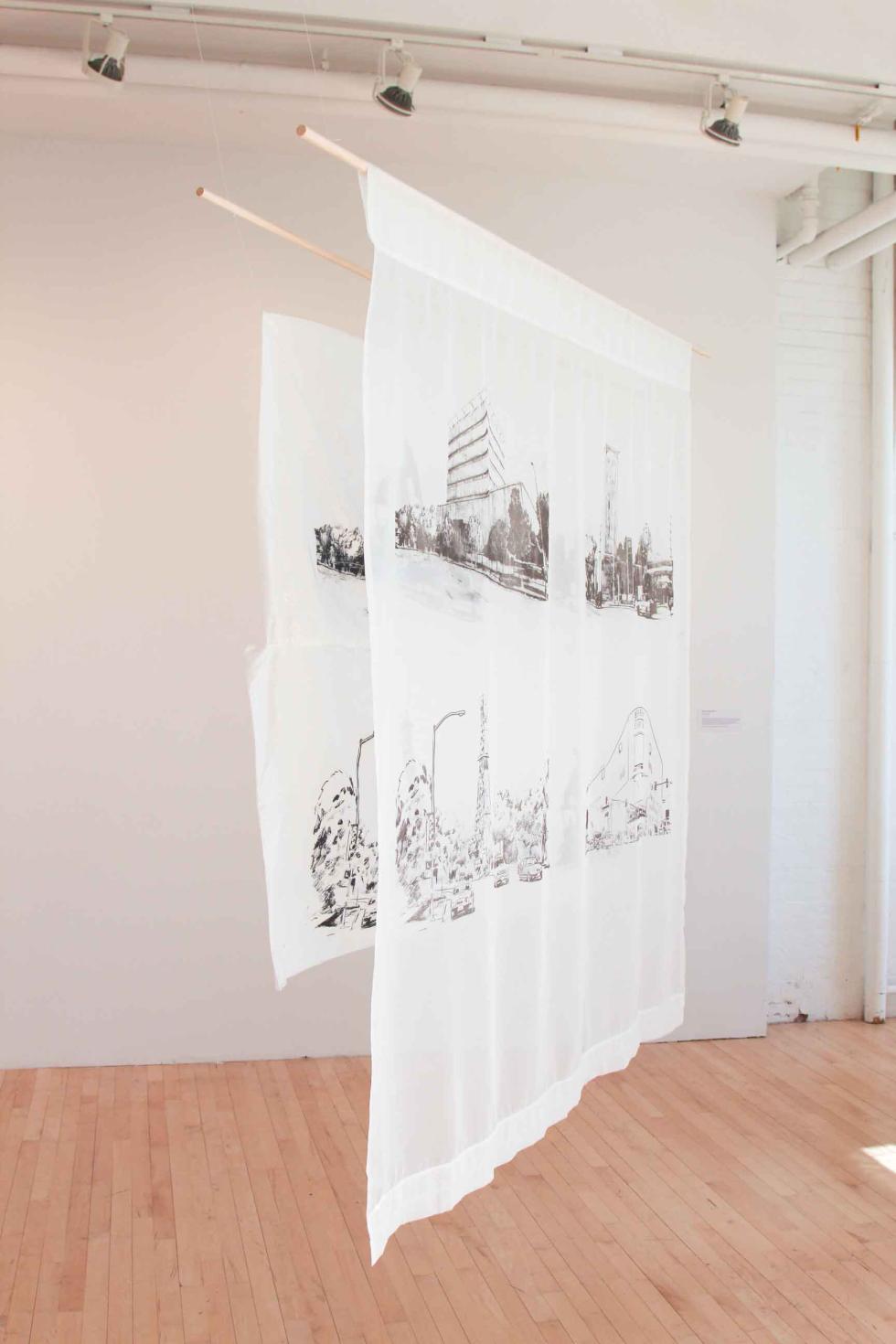 Hanging white banners with four black prints on each banner in a white room.