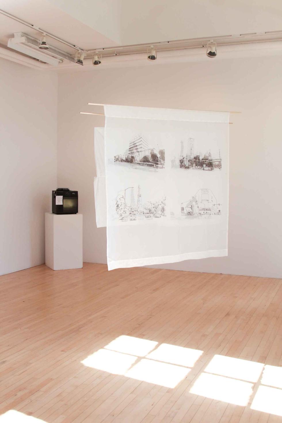 Hanging white banners next to a small tv slide projector on a white pedestal in a white room.